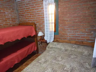 a room with two beds and a brick wall at Mi Niña's in Villa Cura Brochero