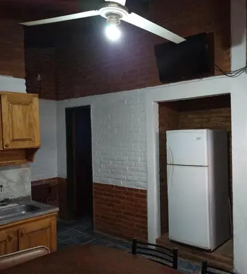 a kitchen with a white refrigerator and a brick wall at Mi Niña's in Villa Cura Brochero