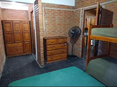 a room with a bedroom with a dresser and a fan at Mi Niña's in Villa Cura Brochero