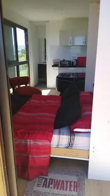 a bedroom with two beds with red sheets and a kitchen at Containers UMI - Un Mundo Infinito in Potrero de Garay