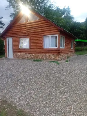 a log cabin with the sun shining on the windows at Posta Nativa in Santa Rosa de Calamuchita