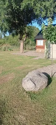 a rock in the middle of a field with a tree at Posta Nativa in Santa Rosa de Calamuchita
