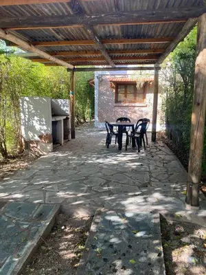 a patio with a table and chairs under a wooden pergola at Abuelo Ramón in Mina Clavero