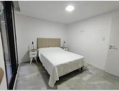 a white bedroom with a bed and a night stand at Sam Lake SL in Villa Carlos Paz