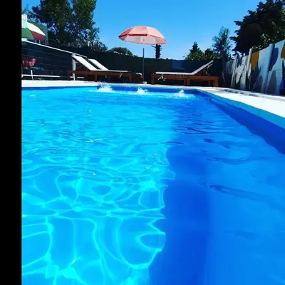 a large blue swimming pool with an umbrella at Complejo cerca del rio in Villa Carlos Paz