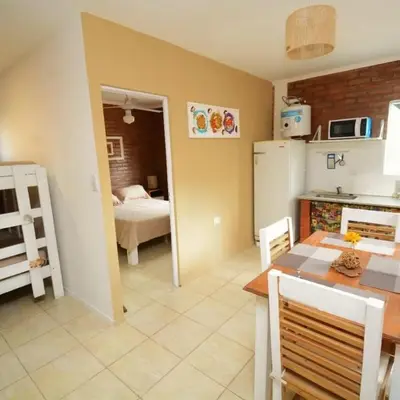 a kitchen with a dining table and a room with a bed at Complejo cerca del rio in Villa Carlos Paz