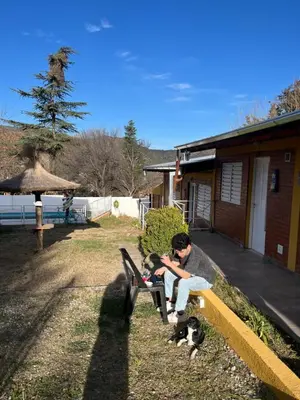 a boy sitting on a bench with a dog at Complejo cerca del rio in Villa Carlos Paz