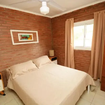a bedroom with a white bed and a brick wall at Complejo cerca del rio in Villa Carlos Paz
