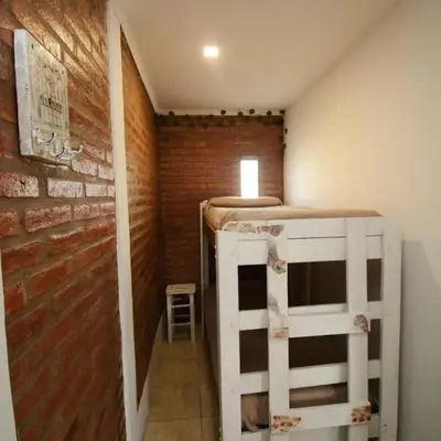 a room with a bunk bed and a brick wall at Complejo cerca del rio in Villa Carlos Paz