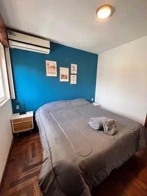 a bedroom with a large bed with a blue wall at Departamento moderno para 3 personas en Zona Nueva Córdoba in Cordoba
