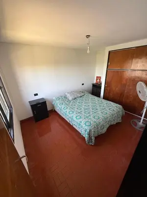 a small bedroom with a bed and a wooden door at Departamento El Fantasio in Villa Carlos Paz