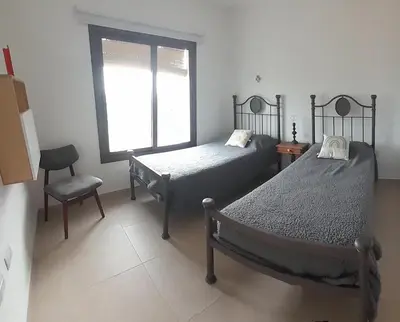 two beds in a room with a window and a chair at Mirador Oeste Potrero de Garay in Potrero de Garay