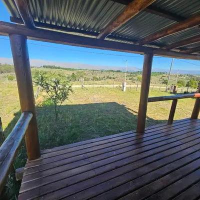 a wooden porch with a view of a field at Espacio Yacanto - Cabaña 1 in Villa Yacanto