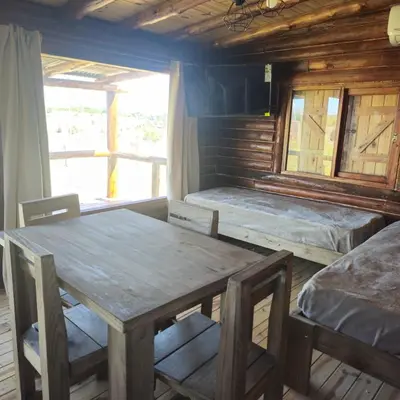 a room with two beds and a table and chairs at Espacio Yacanto - Cabaña 1 in Villa Yacanto