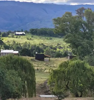 a field with houses and trees and mountains in the background at Espacio Yacanto - Cabaña 1 in Villa Yacanto