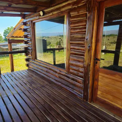 a window on a wooden cabin with a view of a field at Espacio Yacanto - Cabaña 1 in Villa Yacanto