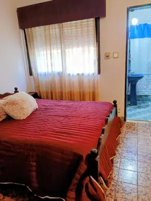 a bedroom with a bed with a red comforter and a window at Casa Santa Rosa de Calamuchita in Santa Rosa de Calamuchita