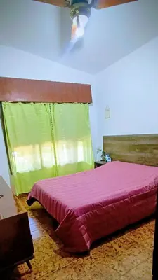 a bedroom with a pink bed with a green curtain at Casa Santa Rosa de Calamuchita in Santa Rosa de Calamuchita