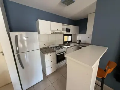 a kitchen with white appliances and a blue wall at Departamento Jacinto en Córdoba in Cordoba