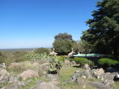 a garden with rocks and a swimming pool at Hostal La Quebrada in Cortaderas