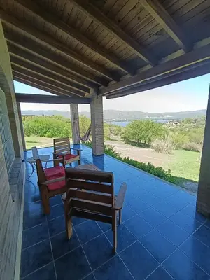 a porch with chairs and a table and a view at Pacha Samay in Villa Parque Siquiman