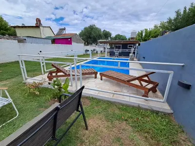 a swimming pool with two benches next to a house at Adonay in Mina Clavero