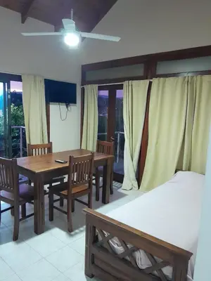 a dining room with a table and chairs and a bed at Cabañas La Bahia Escondida in Potrero de Garay