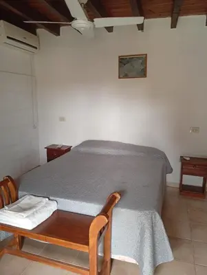 a bedroom with a bed and a wooden chair at Cabañas La Bahia Escondida in Potrero de Garay