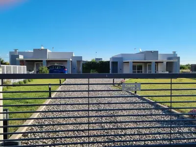 a fence in front of a house with houses at Cabañas NUEVA VIDA in Merlo