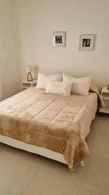a large bed in a white room with two tables at Cabañas NUEVA VIDA in Merlo