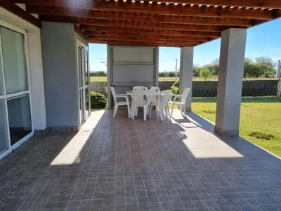 a patio with white tables and chairs on a house at Cabañas NUEVA VIDA in Merlo