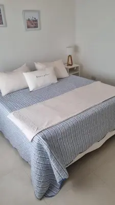 a bedroom with a large bed with a blue blanket at Cabañas NUEVA VIDA in Merlo