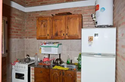 a kitchen with wooden cabinets and a white refrigerator at Cabañas Santísima Trinidad in Villa Cura Brochero