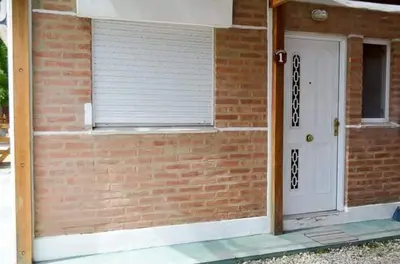 a brick building with a white door and a window at Cabañas Santísima Trinidad in Villa Cura Brochero