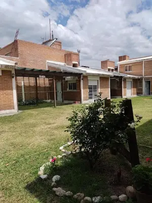a brick building with a bush in the yard at Cabañas Santísima Trinidad in Villa Cura Brochero