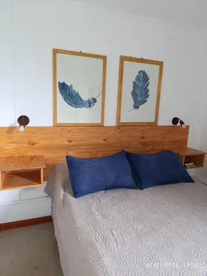 a bedroom with a bed with two pictures on the wall at Cabañas Viena II cerquita de Villa General Belgrano in Villa Ciudad Parque