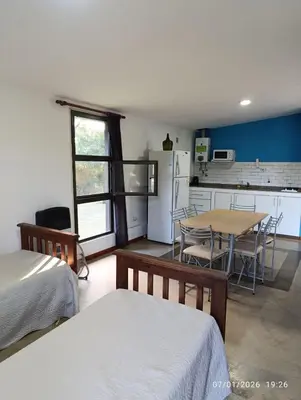 a room with a kitchen and a table and chairs at Cabañas Viena II cerquita de Villa General Belgrano in Villa Ciudad Parque