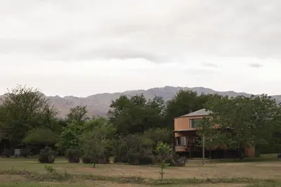 a house in a field with mountains in the background at Cabañas Bendita Tierra 1 in Los Molles