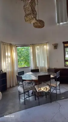 a dining room with a table and chairs and windows at Cabañas Bendita Tierra 1 in Los Molles