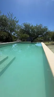 a blue swimming pool with trees in the background at Casita Champaqui in Villa de Las Rosas
