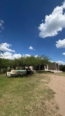 a house with a tree in the middle of a field at Casita Champaqui in Villa de Las Rosas