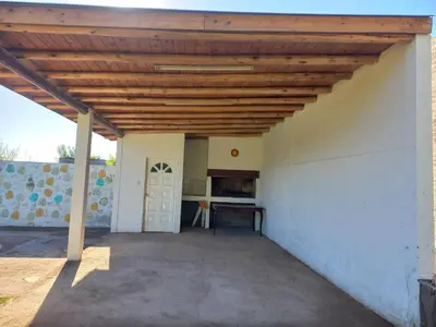 a patio with a wooden roof and a table at Apartamentos Las Margaritas in Villa Santa Cruz del Lago