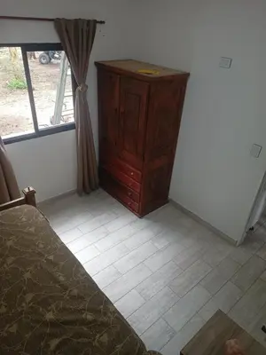 a bedroom with a wooden dresser and a window at Bustos-Ariza in Villa Cura Brochero