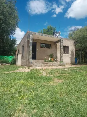 a small house sitting on top of a grass field at Bustos-Ariza in Villa Cura Brochero