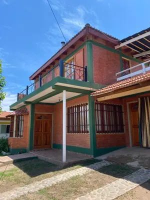 a red brick house with a balcony on top at Casa Mi Sueño in Villa Cura Brochero