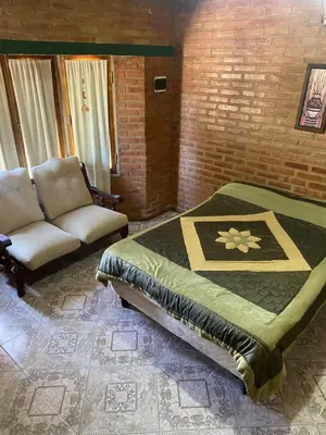 a bedroom with a bed and a couch and a chair at Casa Mi Sueño in Villa Cura Brochero