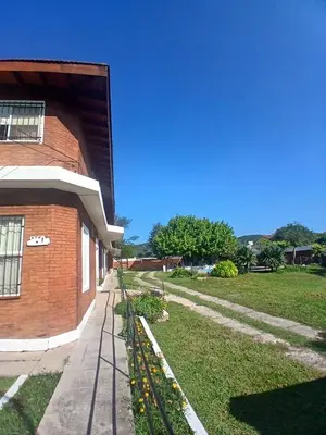 a brick building with a sidewalk next to a yard at Brisas del Norte in Villa Carlos Paz