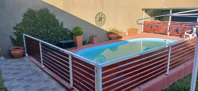 a fence around a swimming pool in a backyard at Departamentos Ecuador in Villa Carlos Paz