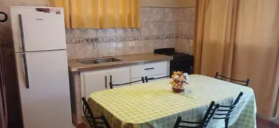 a kitchen with a table with a yellow table cloth and a refrigerator at Departamentos Ecuador in Villa Carlos Paz
