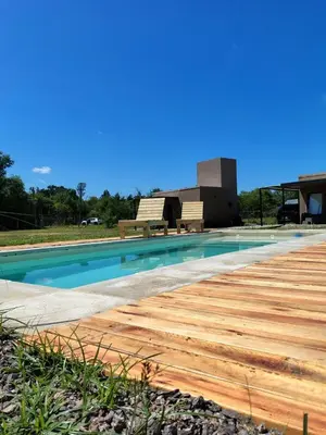 a swimming pool with a wooden deck next to a building at Casasdecampo pasabaxaqui in Villa Anizacate